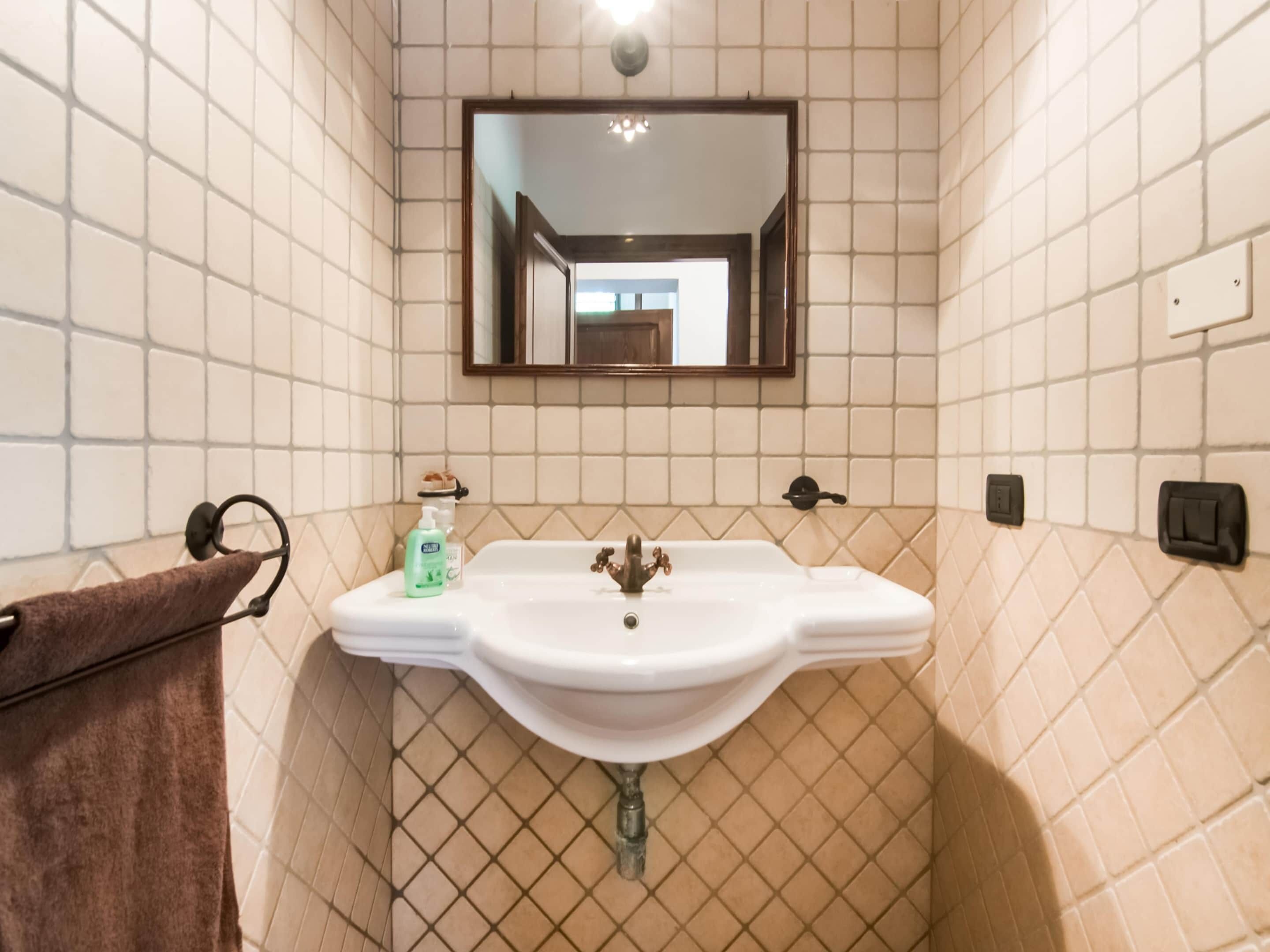 Une salle de bain avec un lavabo blanc, un porte-serviettes et un miroir.