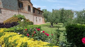 A historic stone building with a garden featuring roses and yellow flowers. - Belvilla by OYO Fienile (Castelfiorentino)