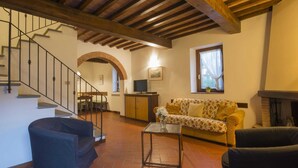 A spacious living area with a staircase, a sofa, a coffee table, and a fireplace. - Belvilla by OYO Fienile (Castelfiorentino)