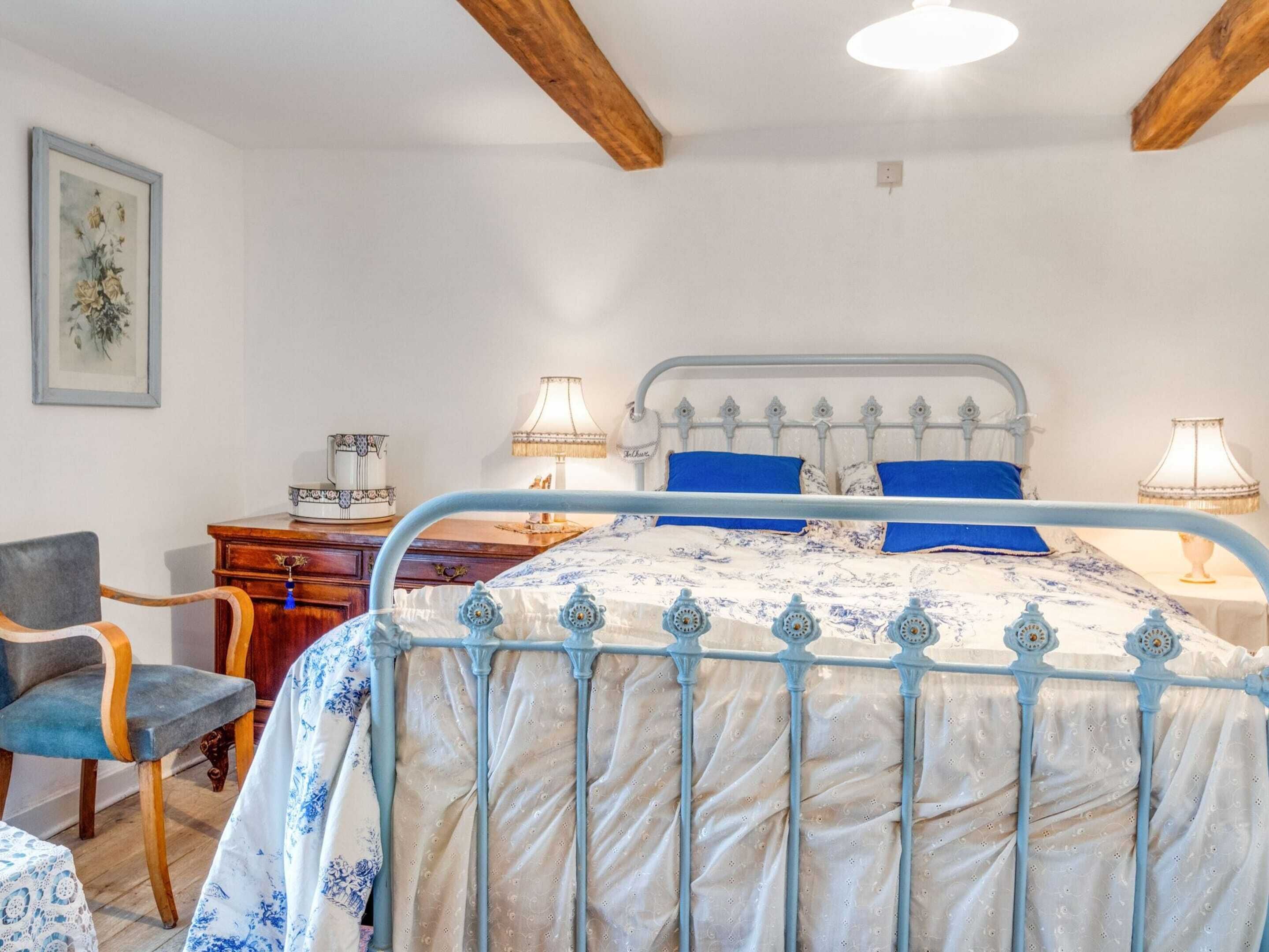 A bedroom with a bed, bedside lamps, a chair, a dresser, and a framed picture on the wall.