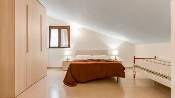 Un dormitorio con cama, mesitas de noche, armario y ventana.