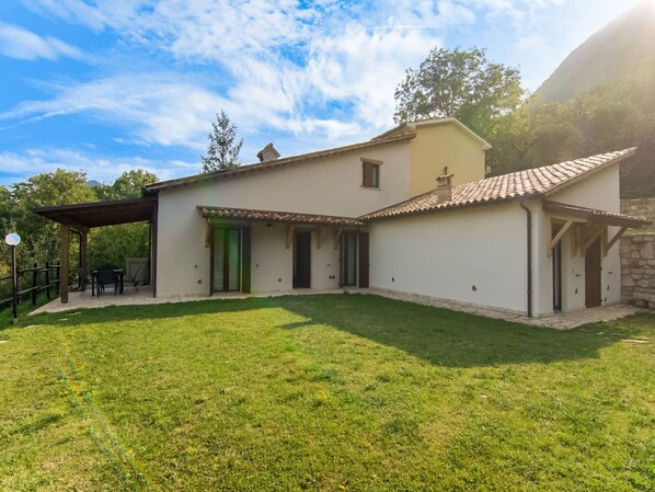 A two-story house with a covered patio and a grassy yard.