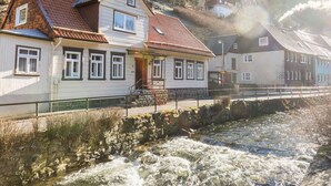 A riverside building with a stone wall and a wooden bridge. - Holiday Home With Private Terrace (Clausthal-Zellerfeld)