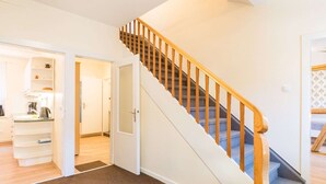 A staircase with wooden handrails leading to an upper floor. A kitchen area with a countertop and appliances is visible on the left. - Holiday Home With Private Terrace (Clausthal-Zellerfeld)