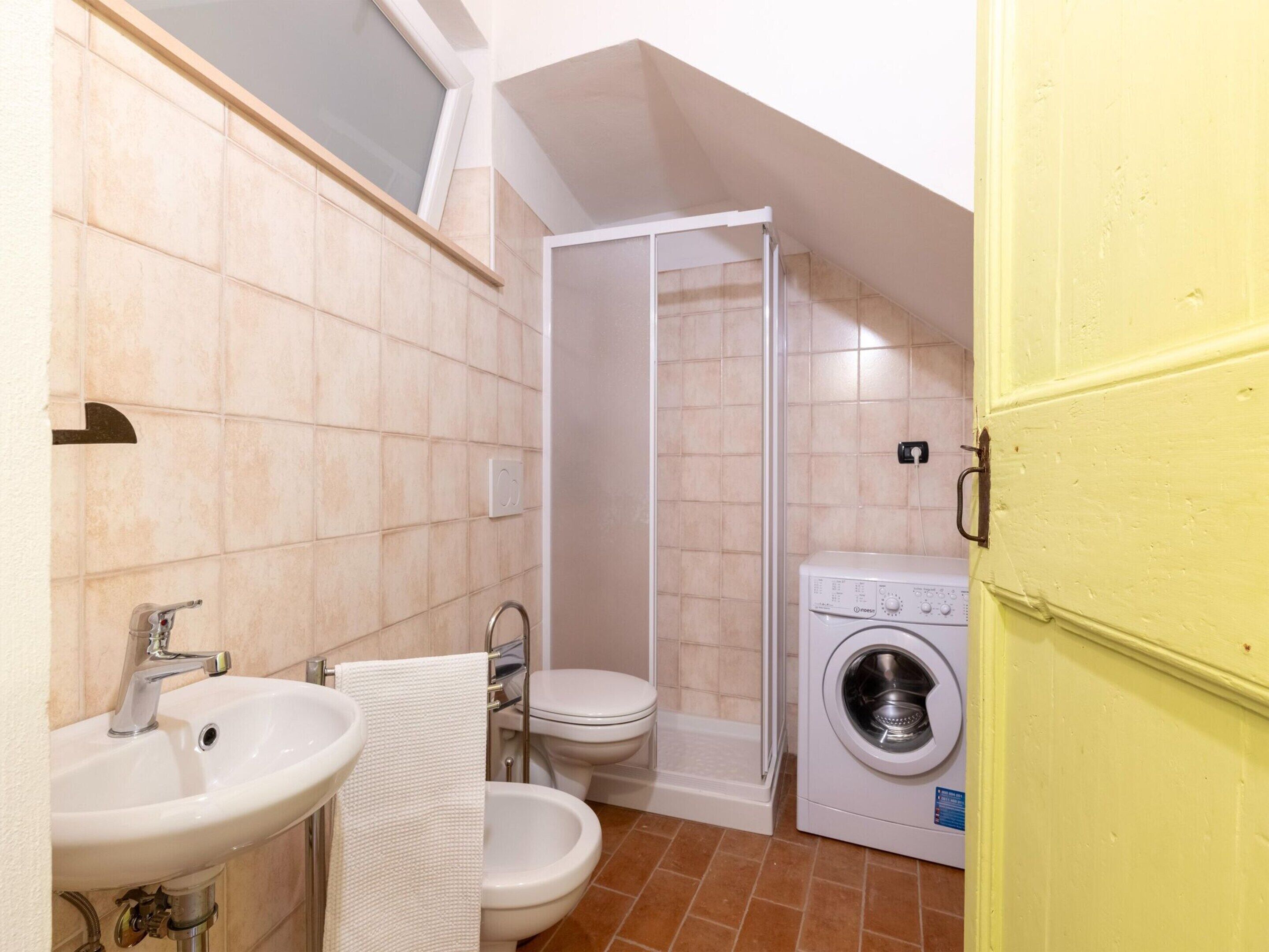 Un baño pequeño con lavamanos, inodoro y lavadora.