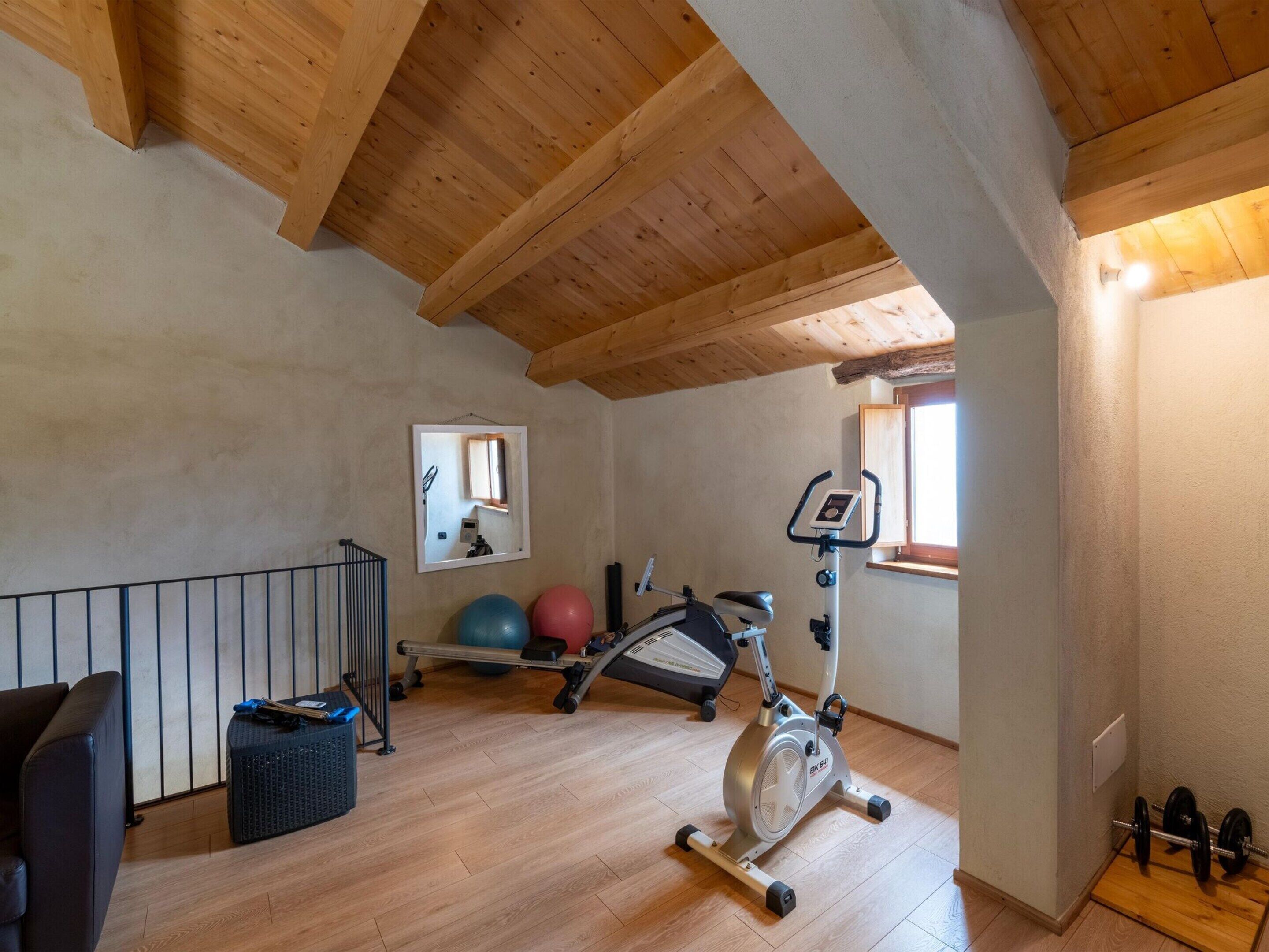 Une salle de sport équipée de matériel d’exercice, d’un miroir et d’une fenêtre.