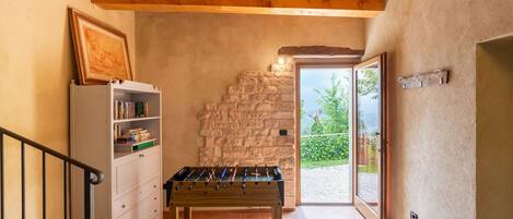 A cozy room with a foosball table, a bookshelf, and a stone wall.