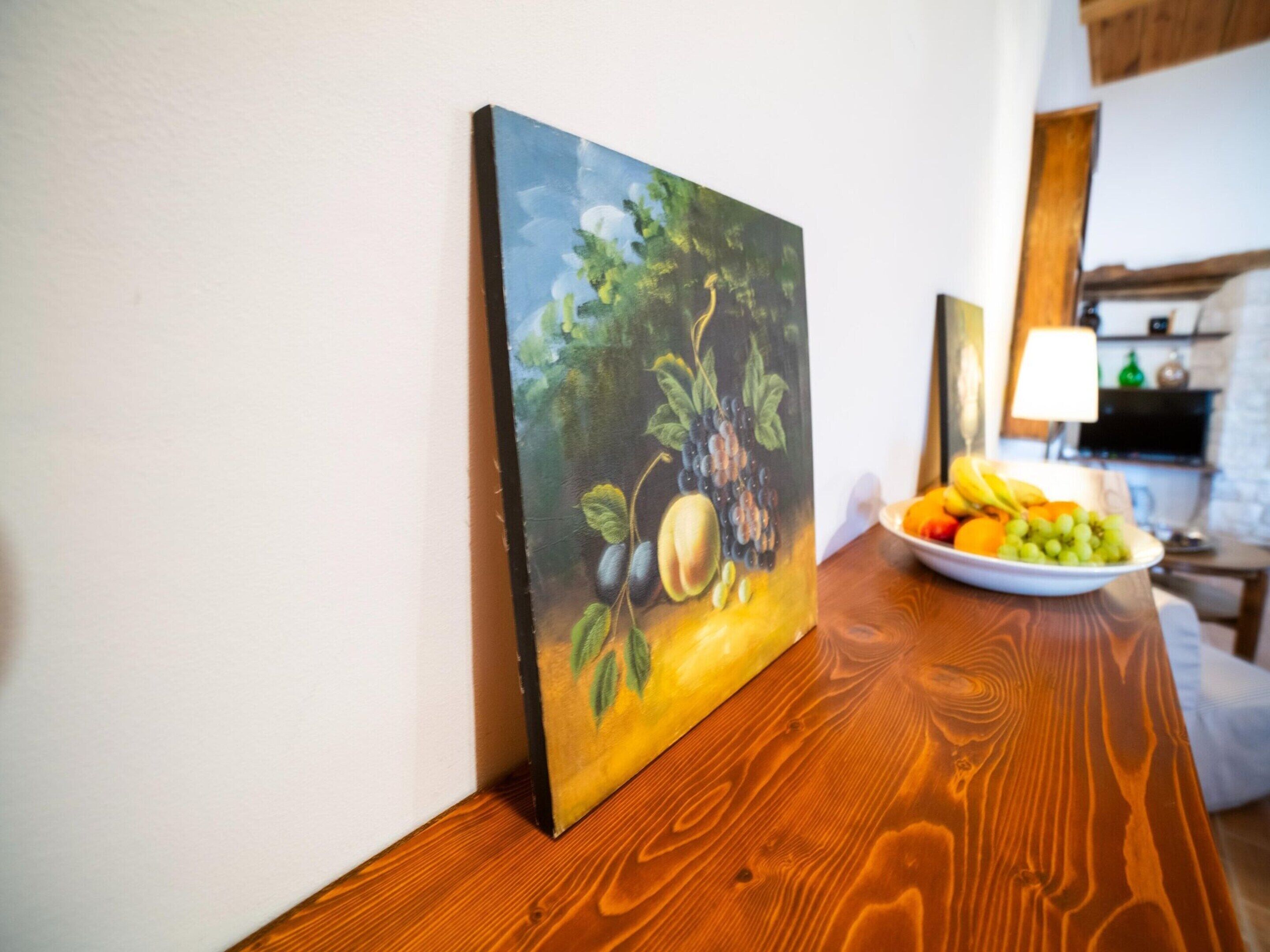 Une peinture représentant des fruits et des légumes sur une table en bois.