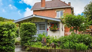 A two-story house with a brick facade, a grey door, and a small porch with a hanging flower pot. - Lovely Cottage in Vierves-sur-viroin With Garden and Terrace (Viroinval)