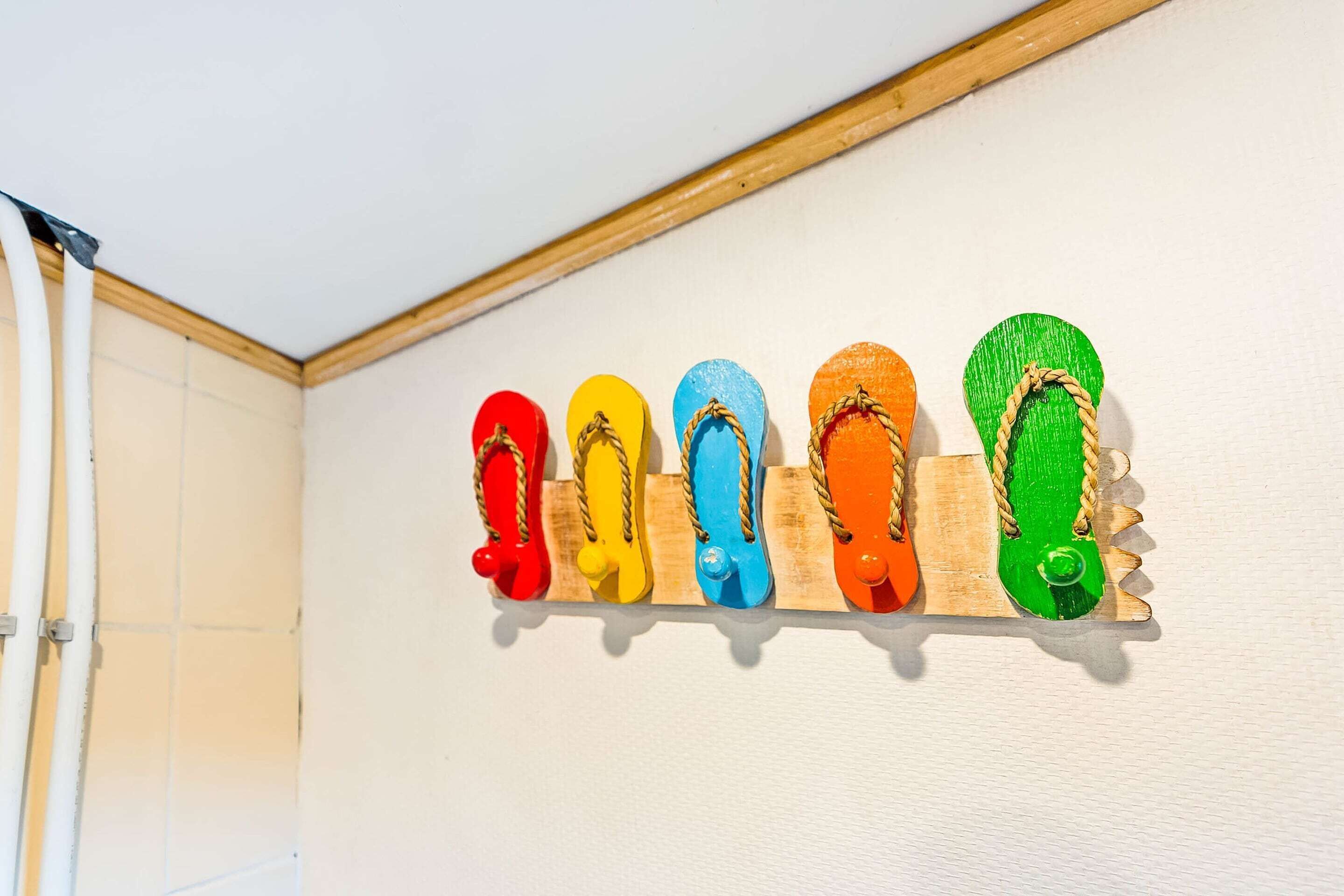 A wall-mounted rack holding six colorful flip-flops.