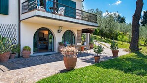 Ein zweistöckiges Haus mit Balkon, Steinweg und Blumentöpfen.