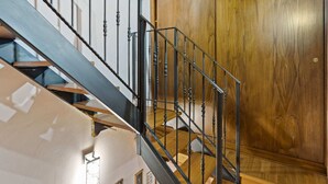 Una escalera con balaustres negros y peldaños de madera que conduce a una puerta de madera.