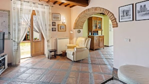 Una sala de estar acogedora con chimenea, un sillón cómodo y un comedor con un arco de ladrillo.