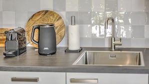 A kitchen with a stainless steel sink, a coffee maker, a kettle, and a wooden cutting board. - Tranquil Farmhouse in Rijsbergen With Hot Tub and Garden (Rijsbergen)