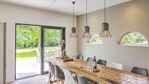 A modern dining area with a large wooden table, black chairs, and pendant lighting. - Tranquil Farmhouse in Rijsbergen With Hot Tub and Garden (Rijsbergen)