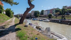 A canal with boats docked, a path beside the water, and buildings in the background. - Holiday Home in Fano Near the Beach (Fano)
