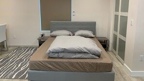 Une chambre à coucher moderne avec un grand lit, une table de chevet, une commode et une armoire.