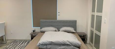 Ein modernes Schlafzimmer mit einem großen Bett, einem Nachttisch, einer Kommode und einem Kleiderschrank.
