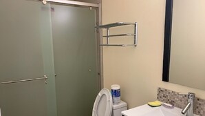 Une salle de bain comprenant des toilettes, une douche, un lavabo et un miroir.