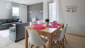 A modern kitchen with a dining table, white chairs, and a decorative wall sign. - Lovely Apartment in Novalja near Sea Beach & Town Center (Novalja)
