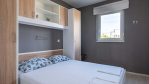 A bedroom with a bed, built-in shelving, a window with a view, and a motivational quote on the wall. - Lovely Apartment in Novalja near Sea Beach & Town Center (Novalja)
