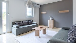 A modern living room with a grey sofa, a wooden coffee table, and a grey couch. - Lovely Apartment in Novalja near Sea Beach & Town Center (Novalja)