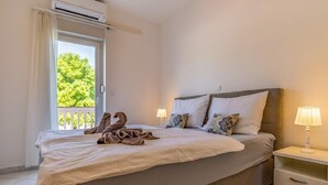 A neatly made bed with a towel sculpture, a bedside lamp, and a view of greenery outside. - Panoramic Apartment in Banjole near Pula Town Center (Medulin)