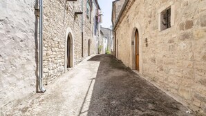 Une ruelle étroite pavée, bordée de bâtiments en pierre dotés de portes et de fenêtres en arc de cercle.