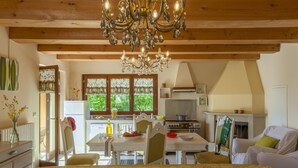 A cozy room with a bed, a dining area with a table and chairs, a kitchen with a stove and a window with a view of greenery.