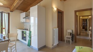 A compact kitchen with modern appliances, a dining area with a table and chairs, and a cozy living space with a bed and pillows.