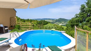 A hot tub with a view of rolling hills and a wooden fence.