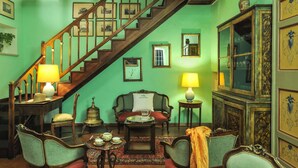 Quarto tradicional com escada, móveis antigos e quadros nas paredes.