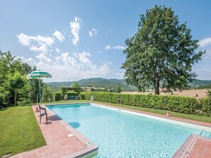 Relax by the pool surrounded by lush greenery and a majestic tree.