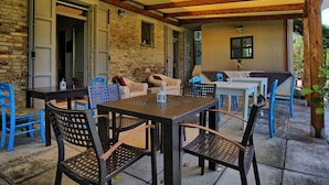 An outdoor patio with a wooden ceiling, brick walls, and a table with chairs.