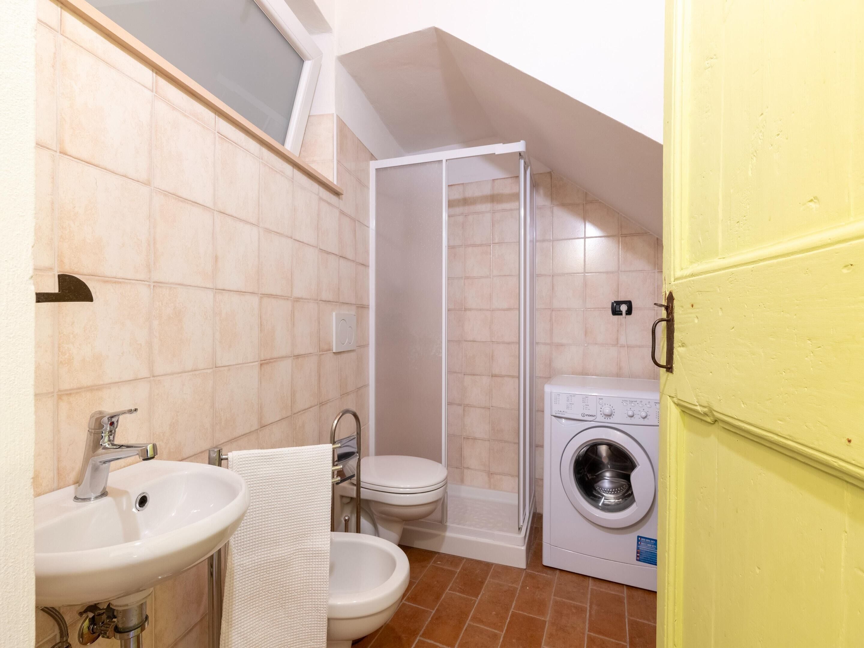 A compact bathroom with a sink, toilet, bidet, and washing machine.