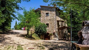 A stone building with a rustic appearance, a gravel path leading up to it, and a wooden structure to the right. - Tuscan Countryside Stay (Casole d'Elsa)