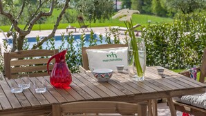 A wooden table with a red vase, a clear glass vase with flowers, a bowl, and a white bag with text.