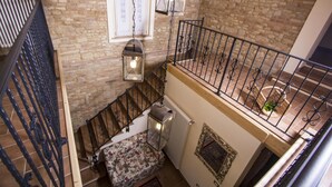 A multi-level interior with a stone wall, a wooden staircase, a metal railing, and a patterned bench. - Holiday Home in Fano Near the Sea (Fano)