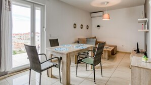 A modern living room with a dining area, large windows, and a view of the city. - Scenic Apartment in Novalja near Trg Loža & Zrče Beach (Novalja)