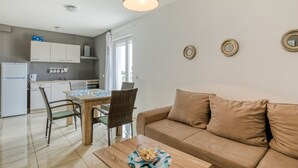 A modern living room with a brown sofa, a wooden coffee table, and a dining area with a table and chairs. - Scenic Apartment in Novalja near Trg Loža & Zrče Beach (Novalja)