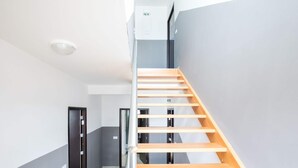 A modern interior with a wooden staircase, grey walls, and a tiled floor. - Scenic Apartment in Novalja near Trg Loža & Zrče Beach (Novalja)