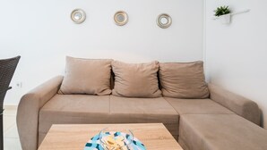 A modern living room with a beige sofa, a wooden coffee table, and three decorative wall plates. - Scenic Apartment in Novalja near Trg Loža & Zrče Beach (Novalja)