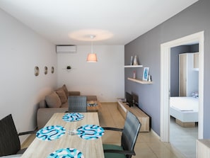 A modern living room with a dining table, chairs, a sofa, and a TV. - Scenic Apartment in Novalja near Trg Loža & Zrče Beach (Novalja)