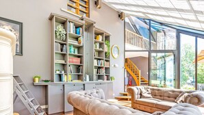 A modern living room with a large sectional sofa, a built-in bookshelf, and a staircase leading to an upper level.