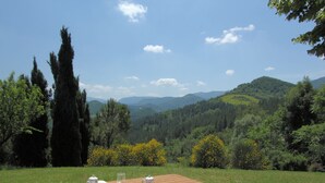 A picnic table with a plate of fruit and a pitcher of water, set against a backdrop of green hills and a clear sky. - Eco-retreat With Pool (Acqualagna)