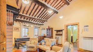 Una sala de estar acogedora con un piano, un sofá y una butaca.