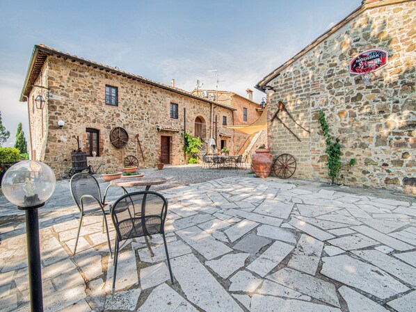 A stone building with a basketball hoop, outdoor seating, and a rustic atmosphere.