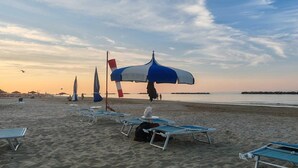 A beach with rows of sun loungers and umbrellas, a calm sea, and a clear sky. - Beautiful Holiday Home With Covered Terrace (San Costanzo)
