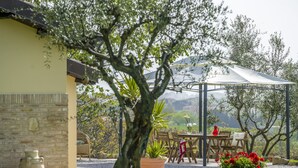 A patio area with a table and chairs, a pergola, and a view of the countryside. - Beautiful Holiday Home With Covered Terrace (San Costanzo)