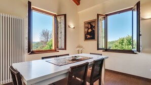 A dining area with a table, chairs, and a view of greenery outside. - Villa in Piandimeleto With Pool & Sauna (Piandimeleto)
